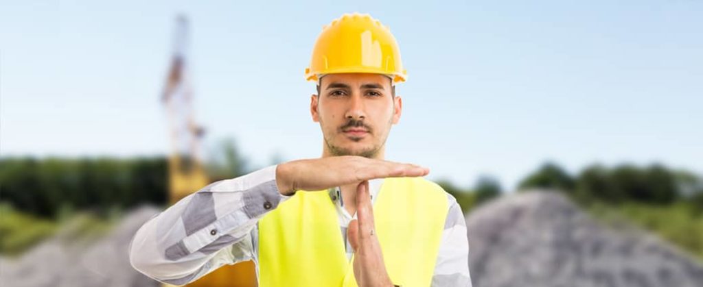 A construction worker signalling a time out, pointing to the fact that one must cover all bases before adopting a mobile form builder