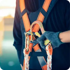 A worker performs a critical pre-use PPE safety inspection on a fall protection harness, ensuring all equipment is safe and compliant before commencing work.