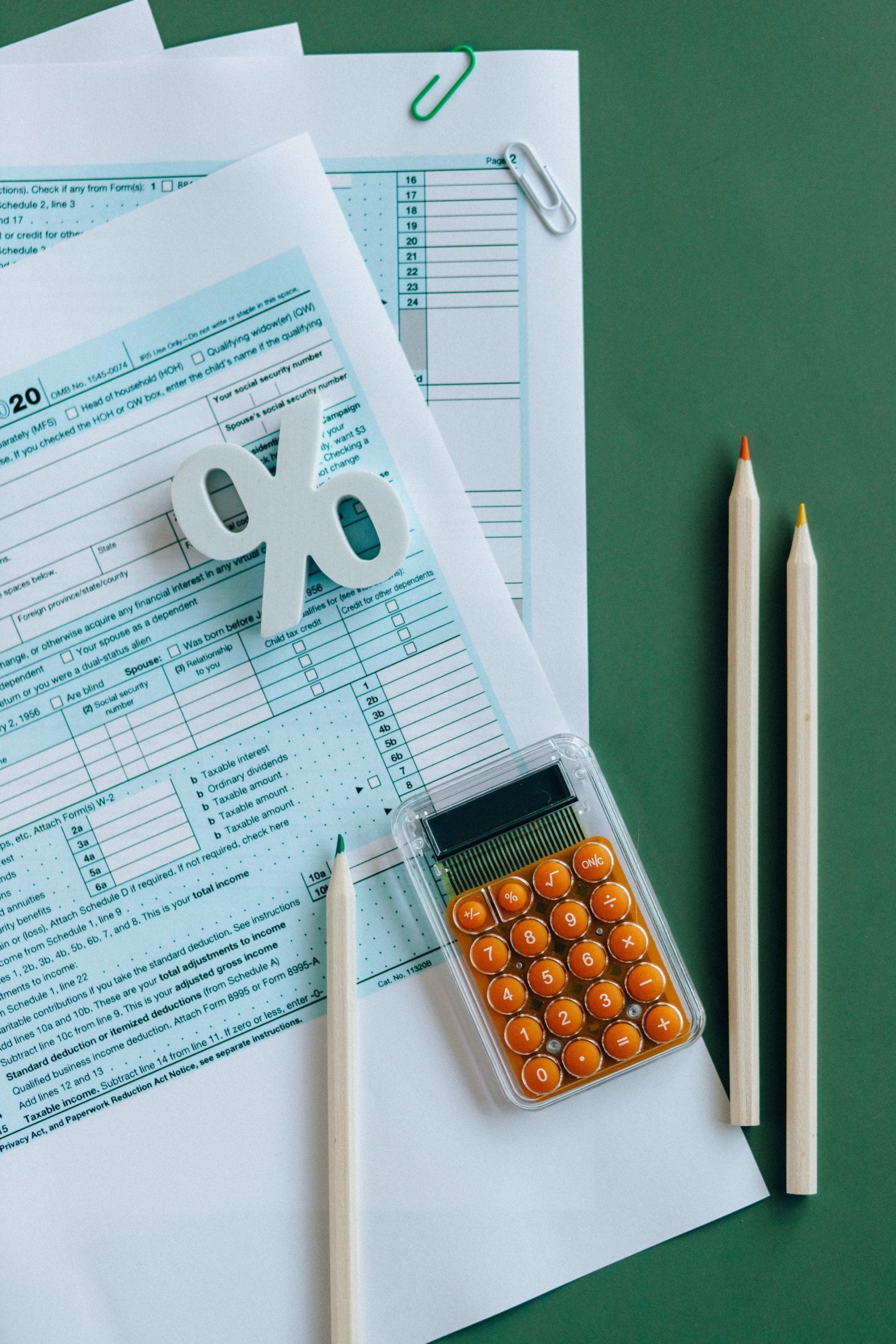 A calculator is sitting on top of a piece of paper next to two pencils.