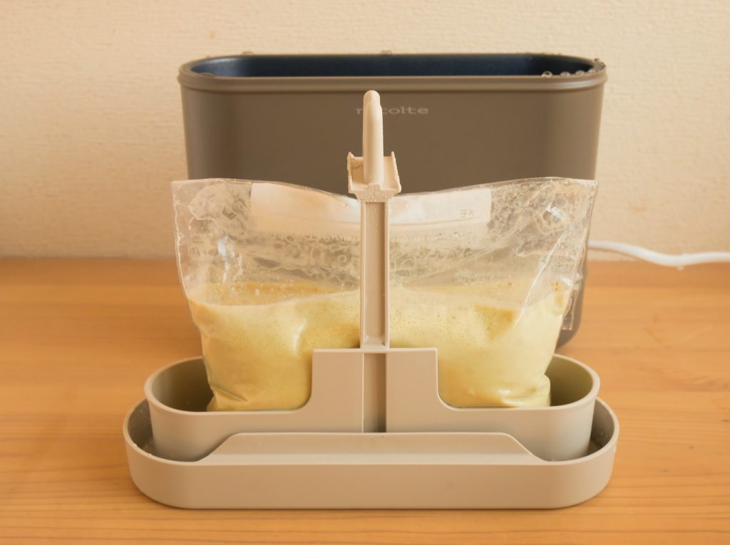 プリン液が入った保存袋を、エッグ&ボイルクッカーのカゴにのせる様子