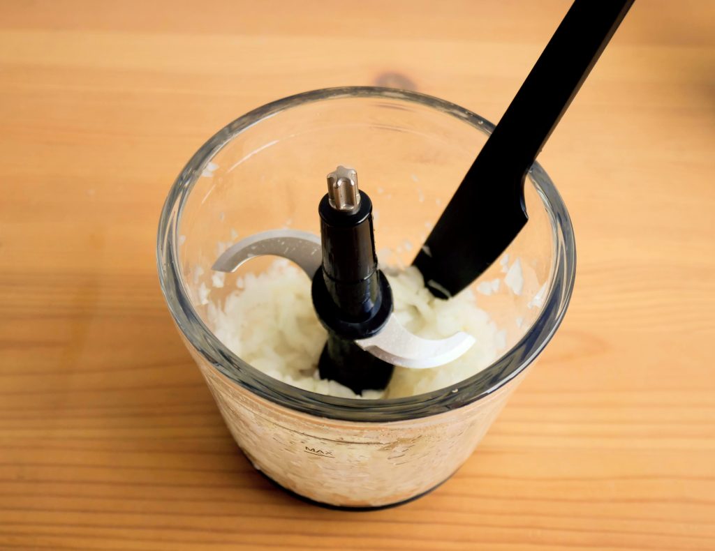 容器のまわりに付いた玉ねぎのみじん切りを、スパチュラで落とす様子