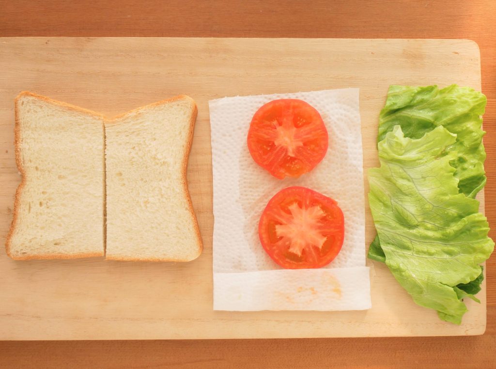 まな板に並べた食パン、トマト、レタス