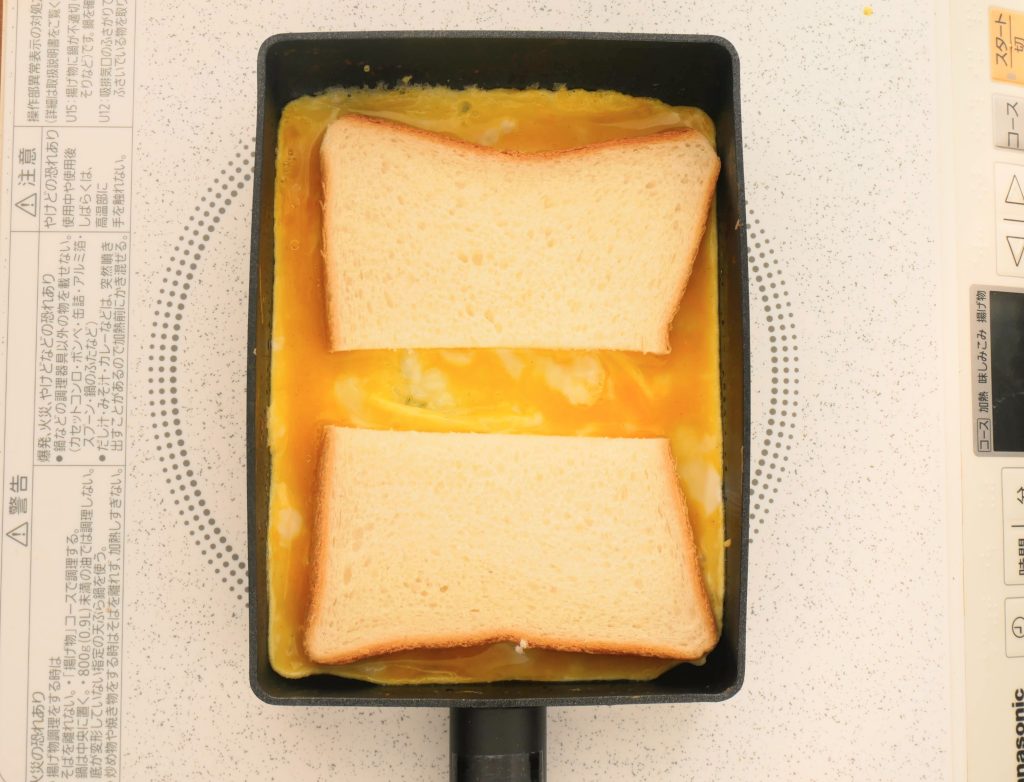 エッグパンに卵を流し、食パンを置く様子