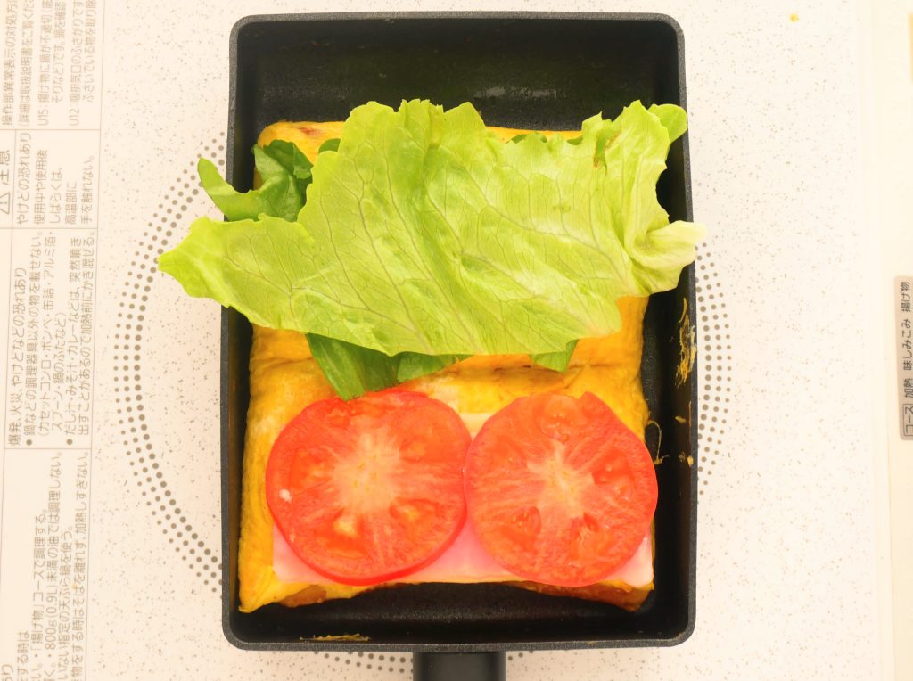 玉子焼きの上に具材をのせる様子