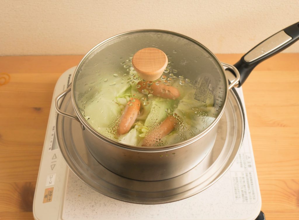 ステンレスでキャベツとソーセージを蒸す様子