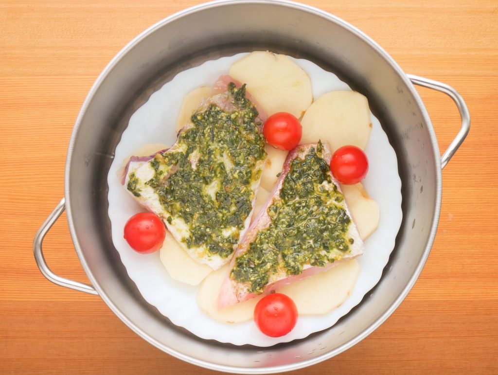 ステンレスせいろに皿にのせたじゃがいもや白身魚をセットする様子