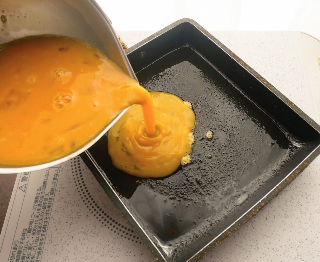 卵焼き器に卵液を流す様子