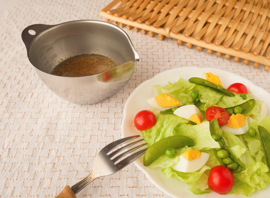 キレッキレボウル11㎝に入った玉ねぎドレッシングと、白い皿に盛られたサラダ