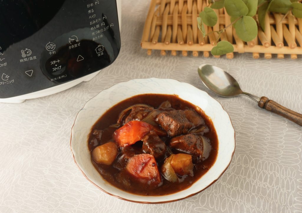皿に盛られたビーフシチューとラクラクッカープロ自動調理鍋