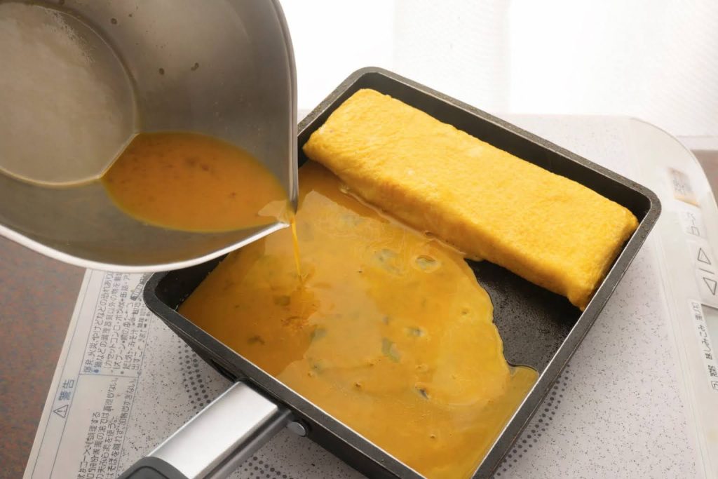 卵焼き器に卵液を流す様子