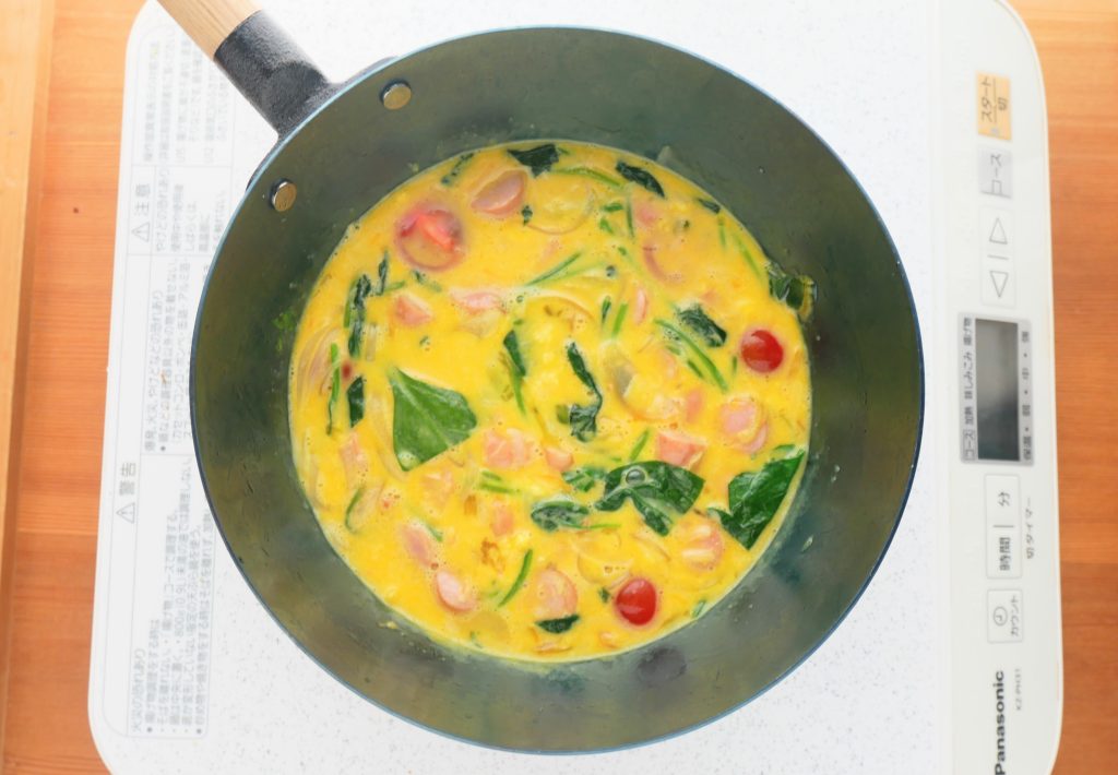 炒めた具材に卵液を流す様子