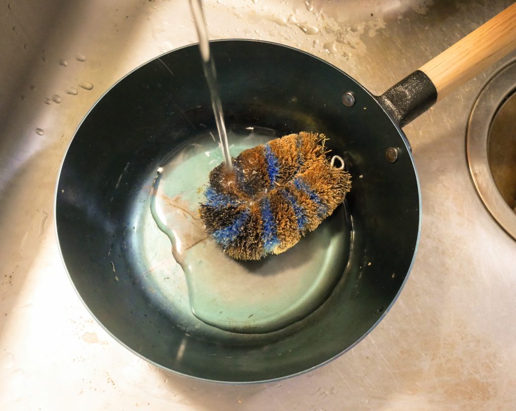 オーブンでも使える鉄フライパンをたわしで洗う様子