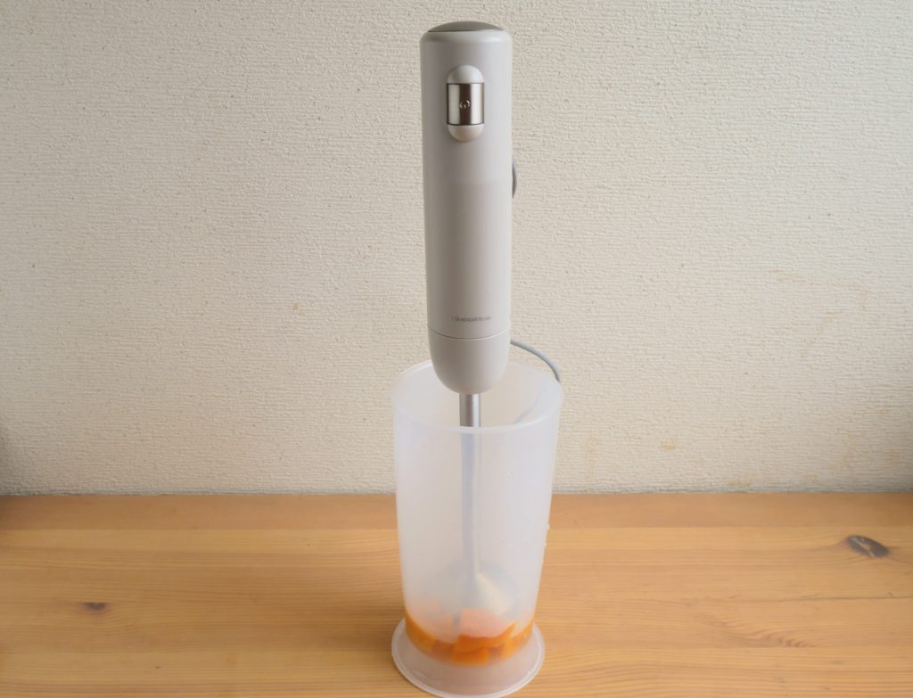 カップに入れたかぼちゃを、レコルトのハンディブレンダーでペーストにする様子