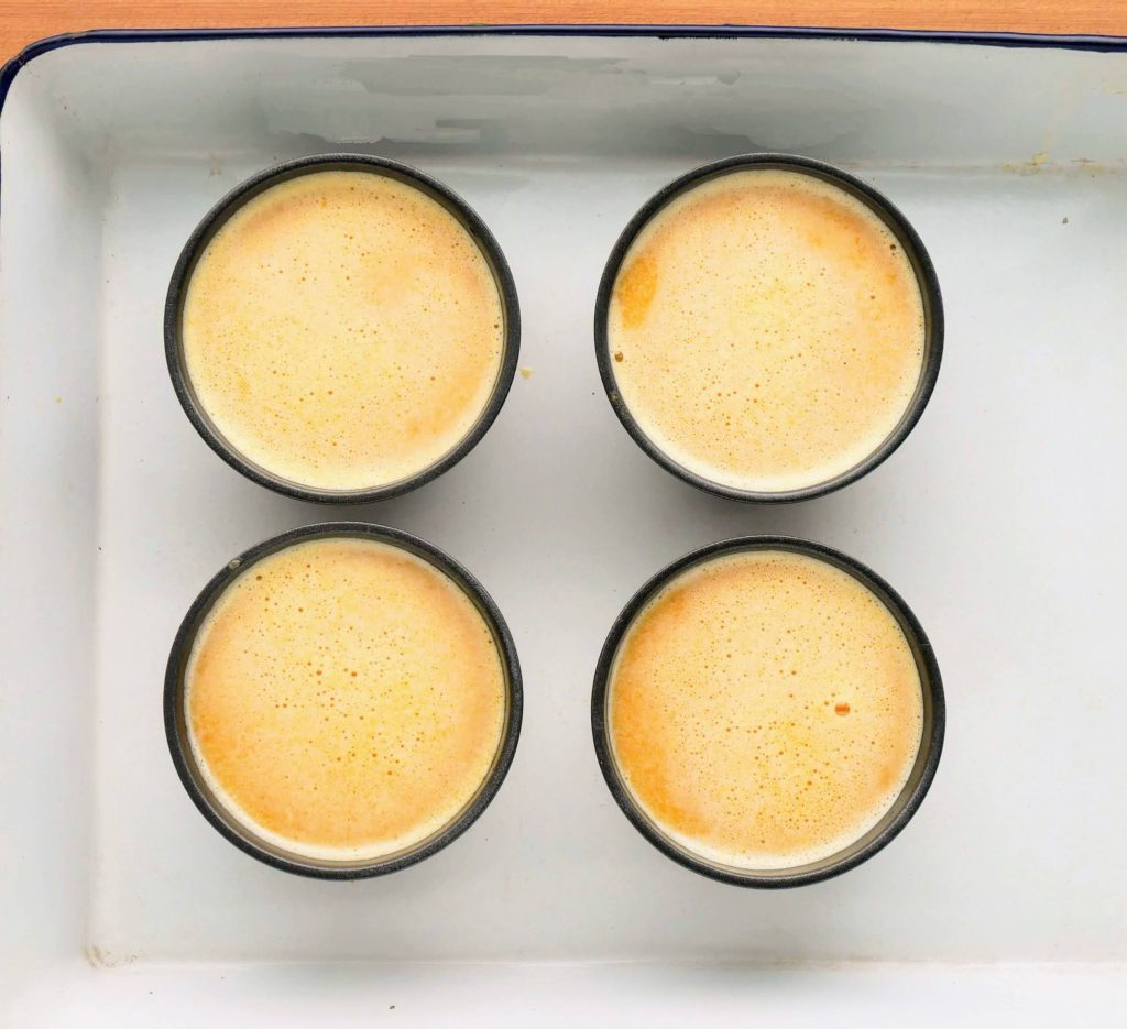 プリンカップに入ったかぼちゃプリンを湯せんにかける様子