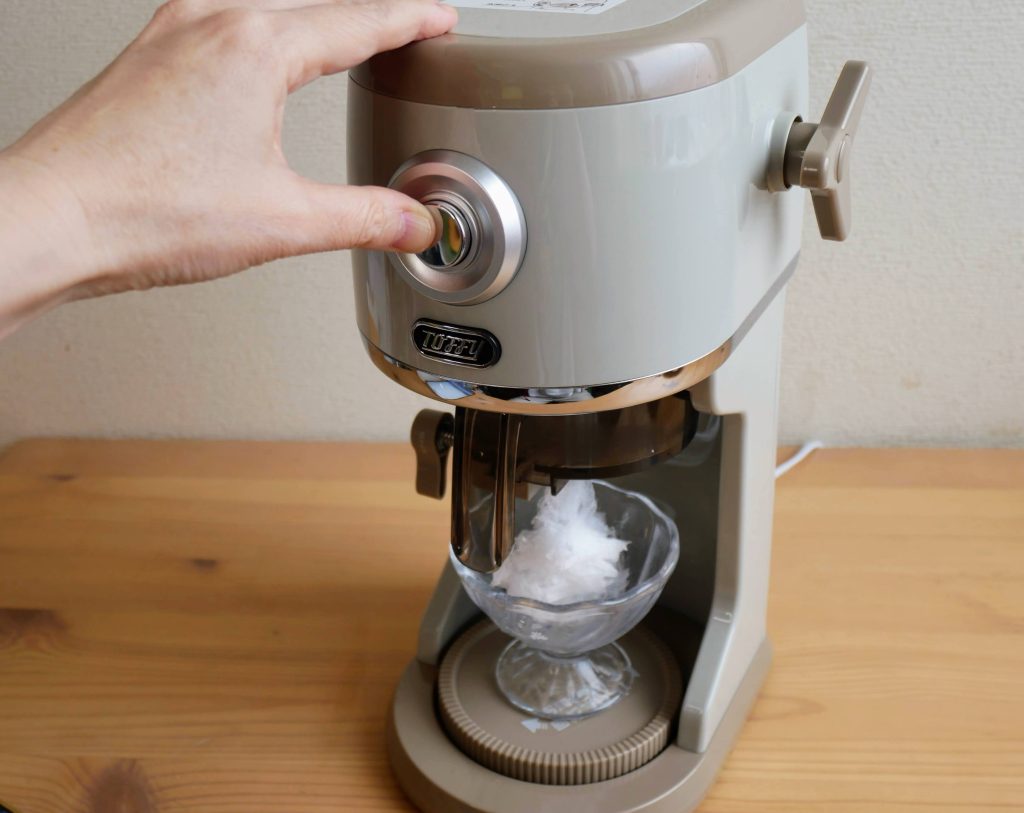 電動ふわふわかき氷器の電源ボタンを押す様子