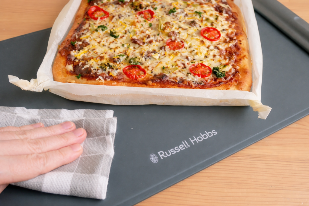 フードウォーマーパッドの汚れをふきんで拭く様子