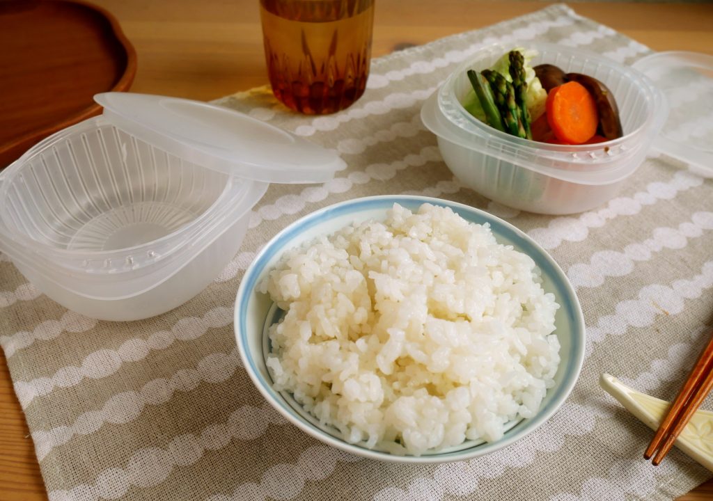 茶碗に盛られたごはんと、蒸気であたためる冷凍ごはん容器に入った温野菜