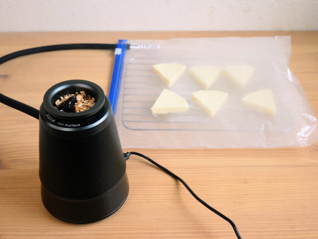 ポリ袋に入ったチーズを、フードスモーカーでいぶす様子