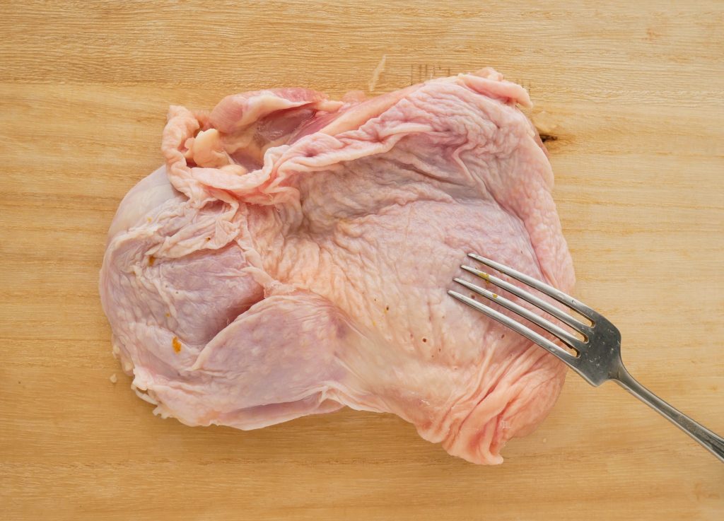 鶏もも肉にフォークで穴をあける様子