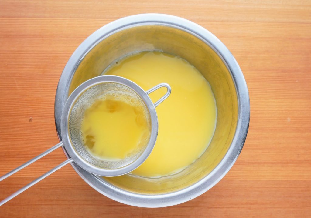 卵液を茶こしでこす様子