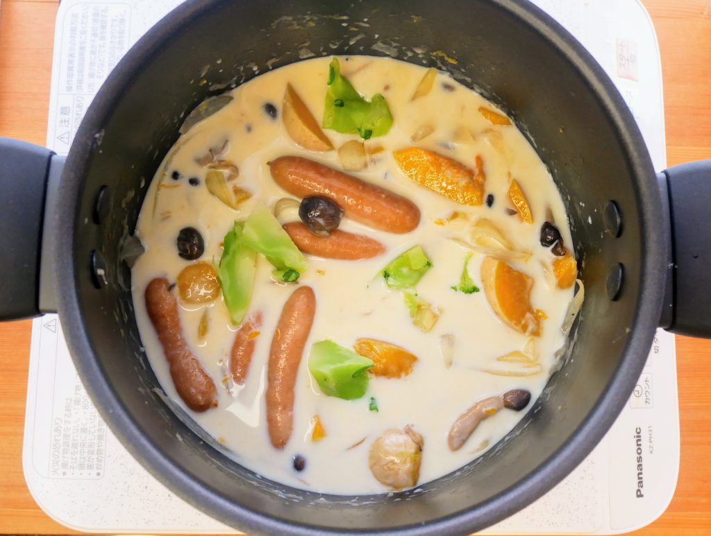 牛乳を加えてかぼちゃシチューを仕上げる様子