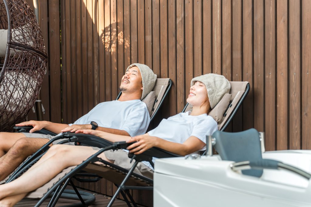 サウナハットをかぶり、屋外のチェアで外気浴をする男女