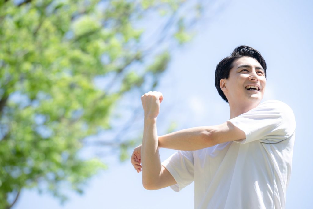 屋外で男性が清々しい表情でストレッチをする様子
